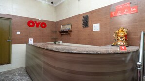A reception desk with a 'OYO' sign, a clock, and a golden statue. - OYO 23300 Seabreeze Residency (Puducherry)