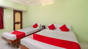 A hotel room with two single beds, each with a red and white bedspread, and a wooden headboard. - OYO 23300 Seabreeze Residency (Puducherry)