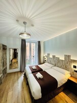 Ein Hotelzimmer mit zwei Betten, einem großen Spiegel, Holzboden und Blick nach außen.