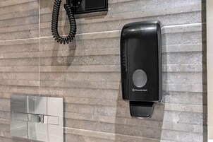 Ein Badezimmer mit Wandtrockner, Telefon und Spiegel.