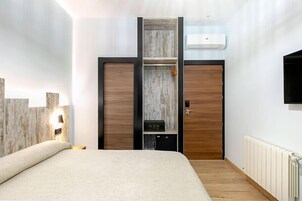 Ein Schlafzimmer mit einem Bett, einem Kleiderschrank, einem an der Wand montierten Fernseher und einer Heizung.