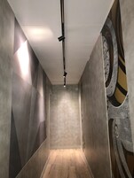 A narrow hallway with a modern design, featuring a light fixture on the ceiling and patterned walls.