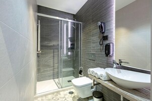 A modern bathroom with a glass-enclosed shower, a white sink, and a toilet.
