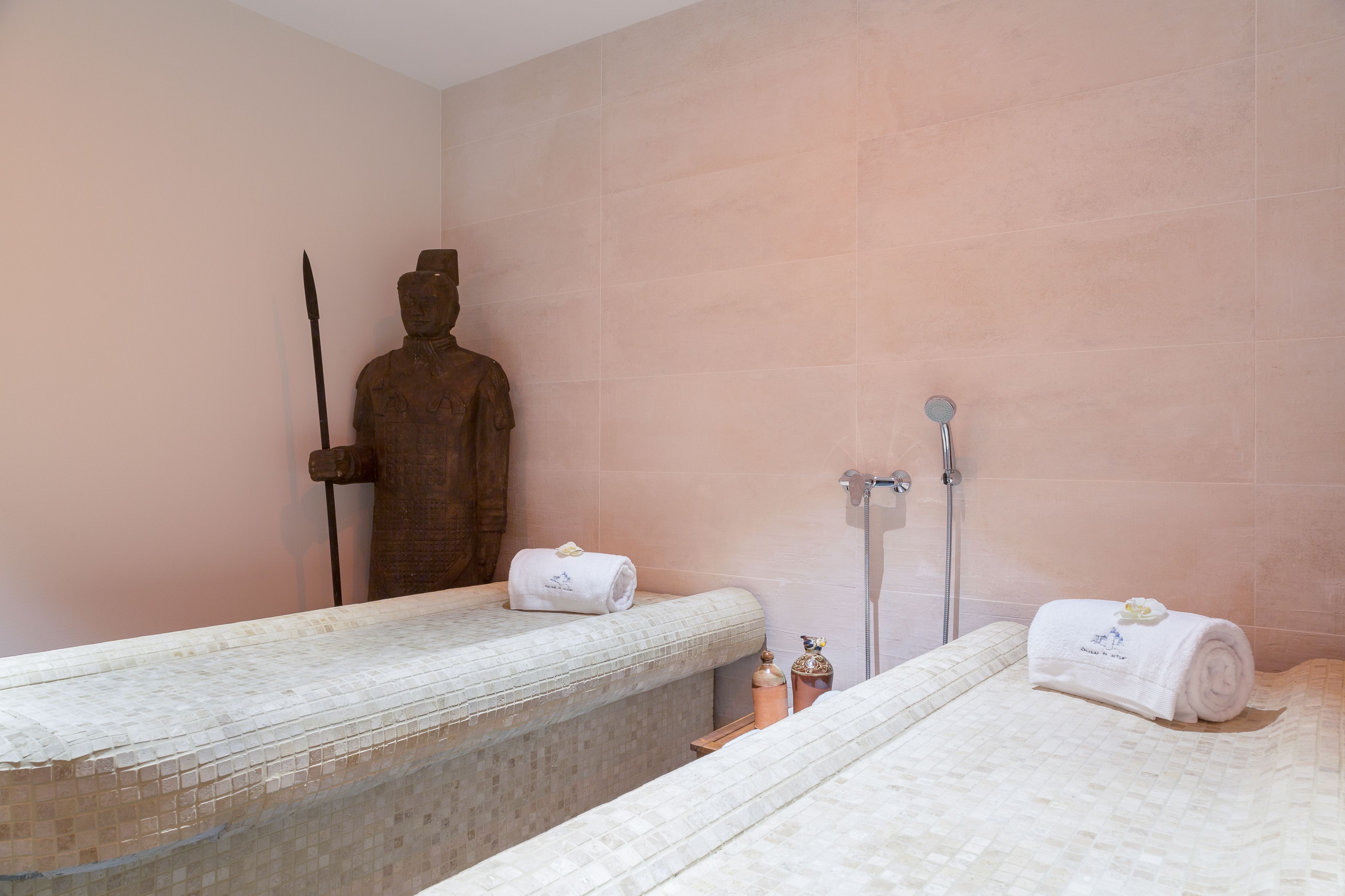 A bathroom with two beds, a statue, and a shower.