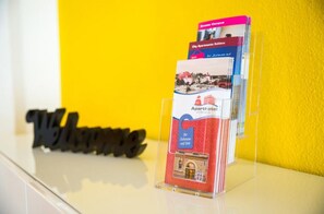 A display of brochures for City Apartments Kobenz, featuring a welcome sign and a clear plastic stand.