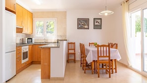 Una cocina moderna con armarios de madera, microondas integrado y comedor con mesa y sillas.