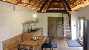 A compact kitchen with a wooden countertop, a sink, and a shelf with baskets. There's a dining area with a table and chairs, and a ladder leading to a door. - Ferienhaus Deutsch Schuetzen (Deutsch Schützen)
