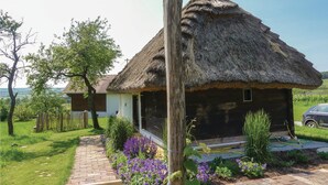 A thatched-roof house with a brick pathway leading to it, surrounded by flowering plants and a grassy area. - Ferienhaus Deutsch Schuetzen (Deutsch Schützen)