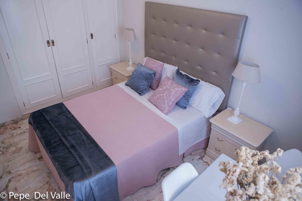 Quarto bem arrumado com cama, mesas de cabeceira e guarda-roupa.