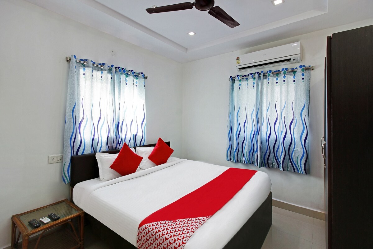 A hotel room with a bed, a small table, a ceiling fan, and an air conditioning unit.