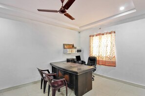 A modern office with a desk, chairs, a ceiling fan, and a window with curtains. - OYO 30151 Golden Hive (Hyderabad)