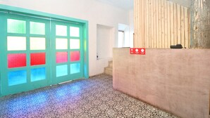 A hotel reception area with a wooden reception desk, a teal door with frosted glass panels, and patterned flooring. - OYO 30593 Heritage Corner (Patiala)