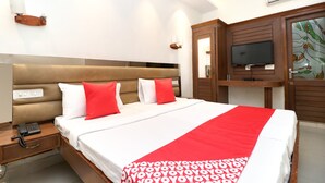 A hotel room with a large bed, a bedside telephone, a TV, and a wardrobe. - OYO 30593 Heritage Corner (Patiala)