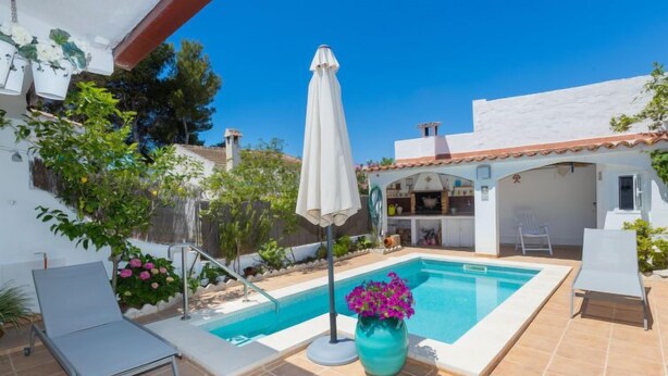 A private pool area with a tiled deck, a lounge chair, a potted plant, and a covered patio with a grill. - Remedios by Interhome (Cunit)