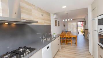 Een koelkast, een oven, een vaatwasser, kookgerei, borden en bestek