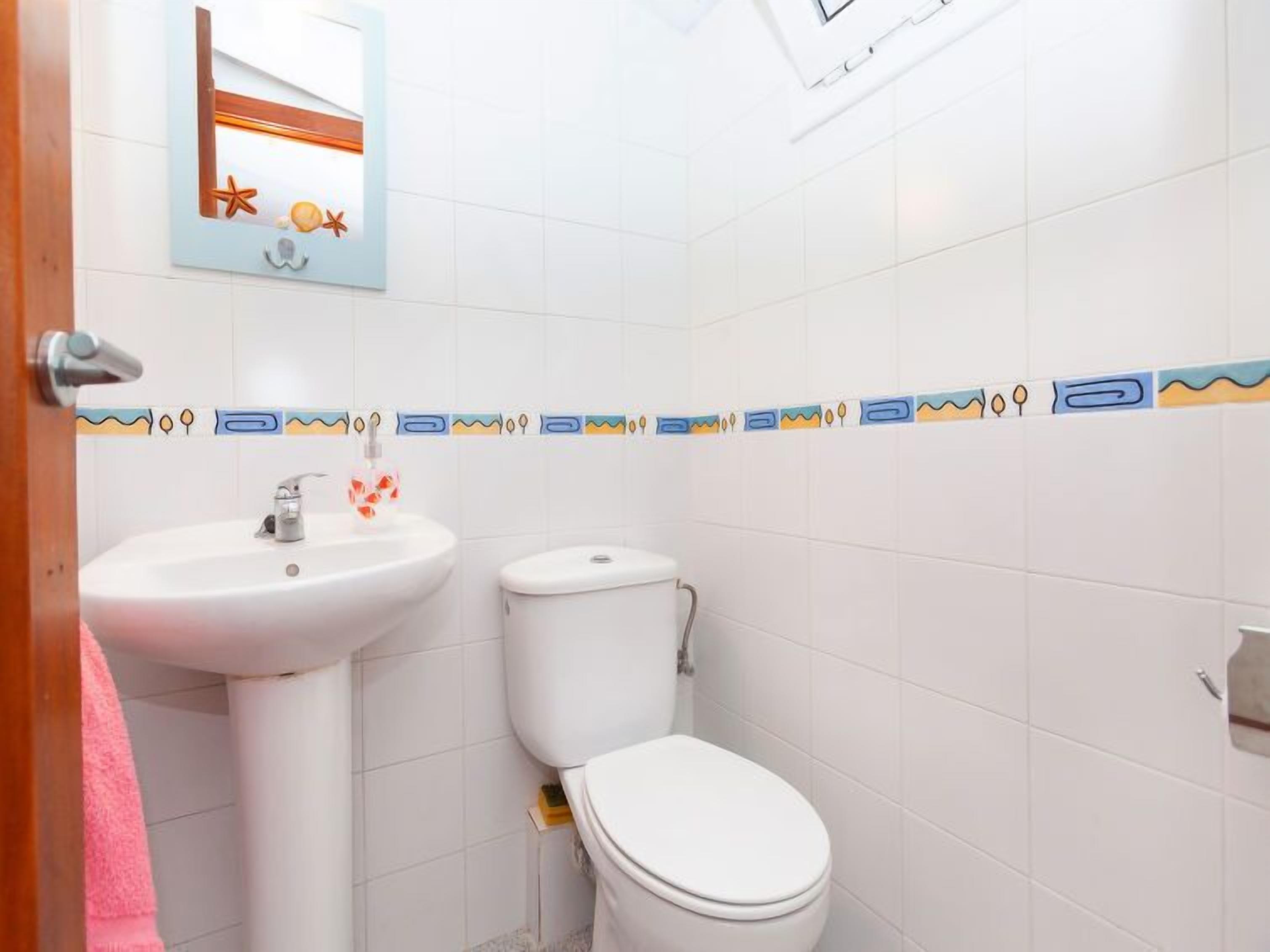 Ein Badezimmer mit einem weißen Waschbecken, einer Toilette und einem Spiegel mit dekorativem Rahmen.