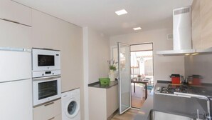 A compact kitchen with a washing machine, a microwave, and a stove. - Remedios by Interhome (Cunit)