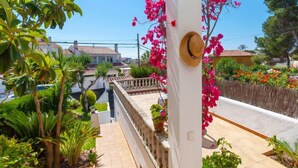 A balcony with a view of a residential street, surrounded by lush greenery and flowering plants. - Remedios by Interhome (Cunit)