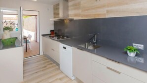 A modern kitchen with a black countertop, stainless steel sink, and a built-in dishwasher. - Remedios by Interhome (Cunit)