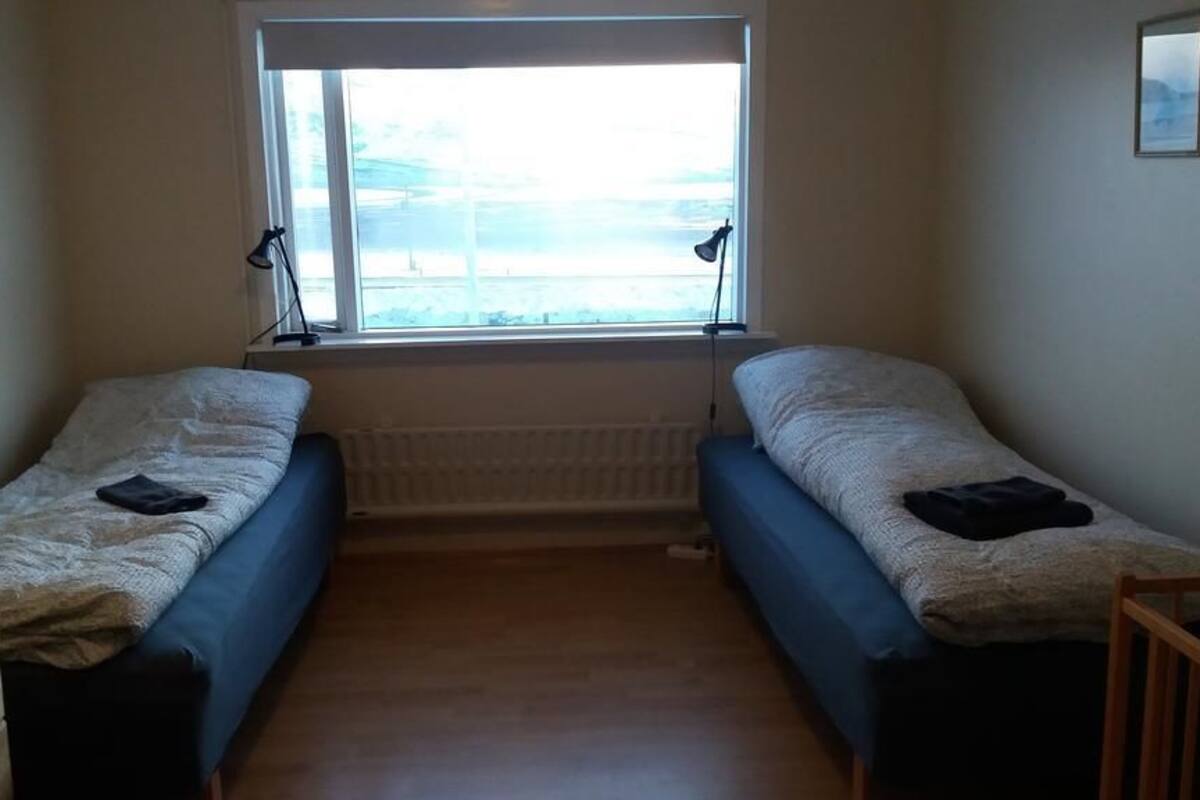 A small room with two single beds, a window with a view, and a radiator.