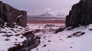 A snowy landscape with a small building in the distance. - Gljúfraborg (Fjardabyggd)