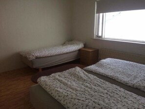 A small room with two single beds, a window, and a radiator. - Gljúfraborg (Fjardabyggd)