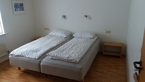 A room with a double bed, two bedside tables, a small wooden stool, and a framed picture on the wall. - Gljúfraborg (Fjardabyggd)