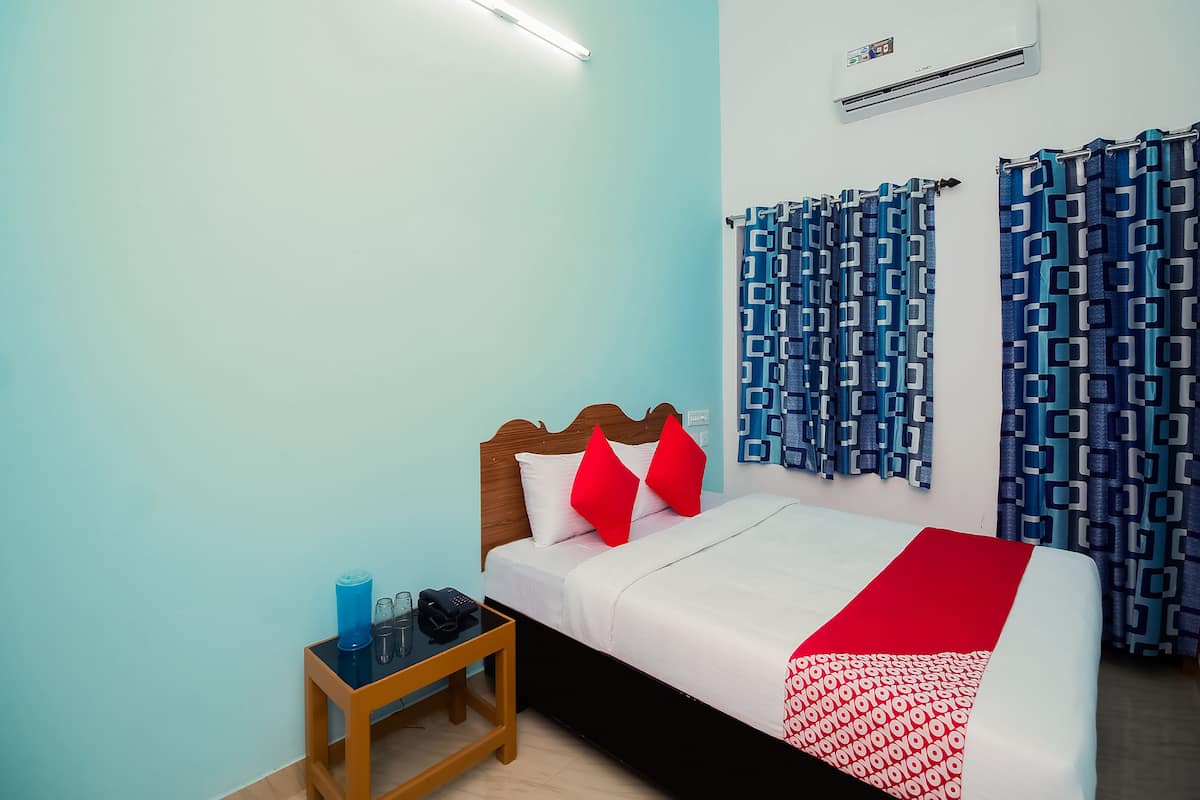 Een netjes ingerichte slaapkamer met een bed, nachtkastje en een airconditioning.
