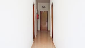 Een smalle gang met een houten deur met daarop het nummer 103 en een brandblusser bevestigd aan de muur.