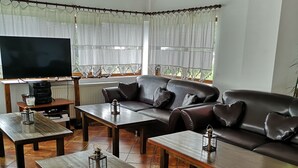 A living room with a sofa, two coffee tables, a TV, and a fireplace. - BonDia (Rasnov)