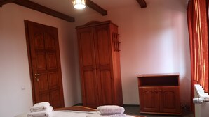 A bedroom with a large bed, wooden wardrobe, and a small cabinet. - BonDia (Rasnov)