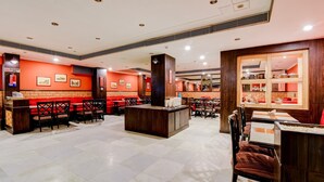 A restaurant with red brick walls, wooden furniture, and a central island. - OYO 39725 Hotel Regent Continental (New Delhi)