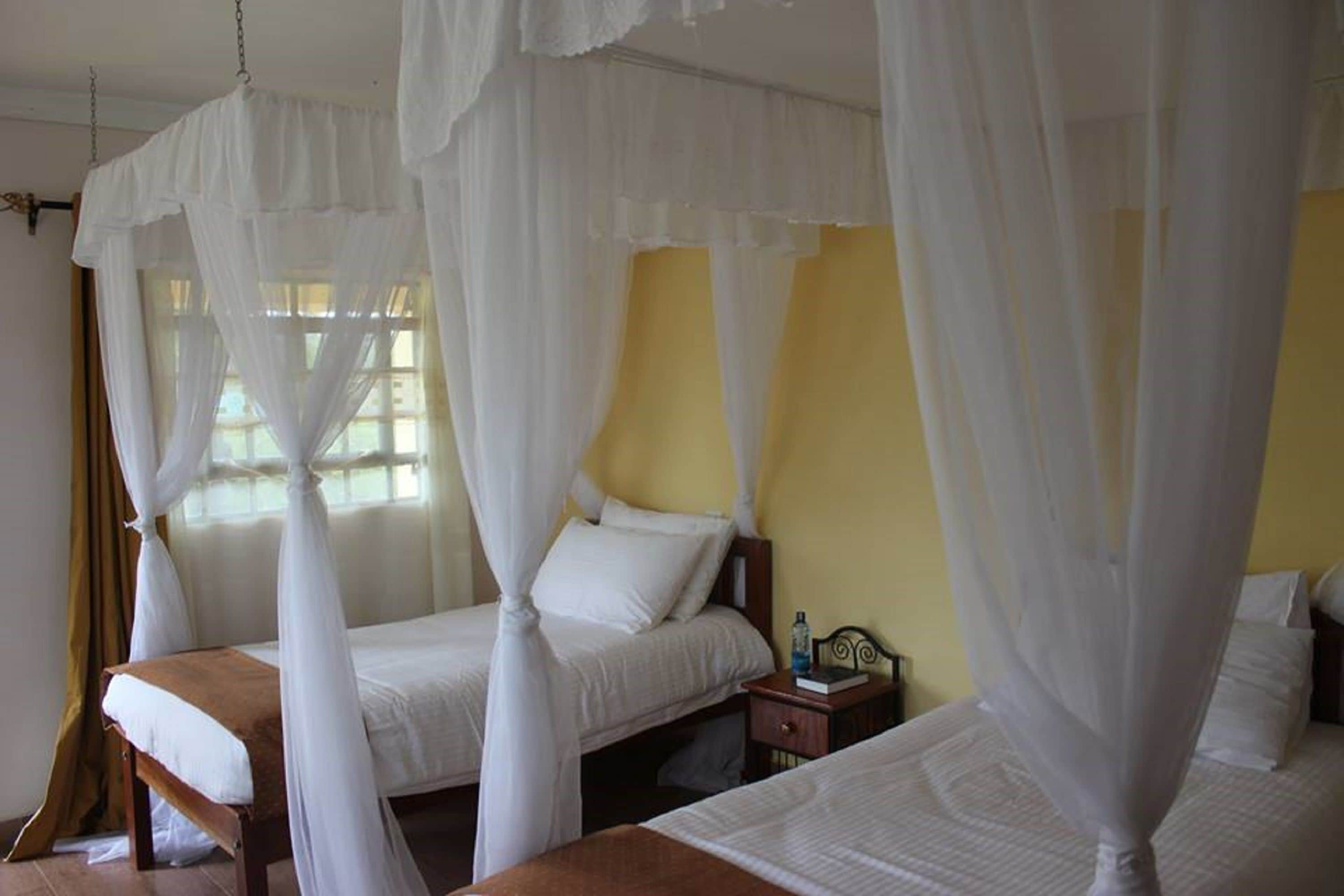 Una habitación con dos camas, cada una con dosel y almohadas blancas.