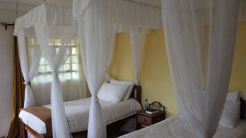 Una habitación con dos camas, cada una con dosel y almohadas blancas.