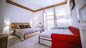Un dormitorio con dos camas, una silla roja, un cabecero de madera, una lámpara blanca y una ventana con vistas.