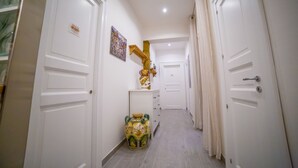 Un pasillo con puertas blancas, un jarrón decorativo y un cuadro en la pared.