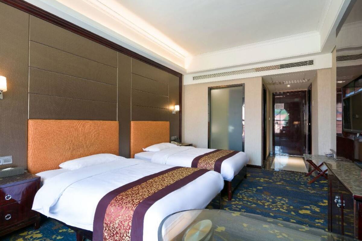 A hotel room with two beds, a large mirror, a desk, and a carpeted floor.