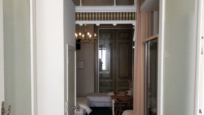 Un pasillo estrecho que conduce a una habitación con una cama, una silla y una mesa.
