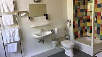 A bathroom with a white sink, toilet, and a shower with colorful tiles.