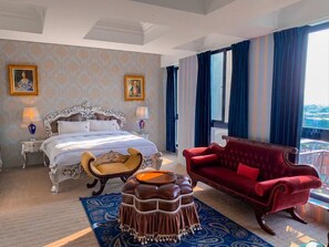 Een hotelkamer met een groot bed, een rode bank, een houten stoel en een kamerbreed tapijt.
