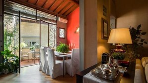 Un coin repas avec une table dressée pour deux personnes, un canapé et une lampe.