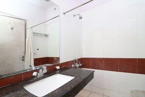 A bathroom with a white sink, a mirror, a shower, and red-tiled walls. - OYO Townhouse 117 Punjabi Bagh (New Delhi)