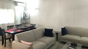 A living room with a beige sofa, a dining table with chairs, and a small coffee table.