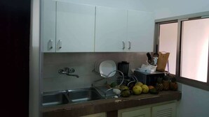 A kitchen with white cabinets, a stainless steel sink, and a window with a view.