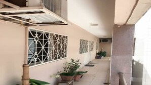 A corridor with potted plants, air conditioning units, and a tiled floor.