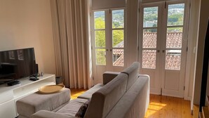 A modern living room with a sofa, a TV, and a wooden tray. - Mezzanine Apartment in the heart of Guimarães. (Guimarães)