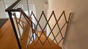 A wooden staircase with a black metal handrail and a wooden lattice barrier. - Mezzanine Apartment in the heart of Guimarães. (Guimarães)