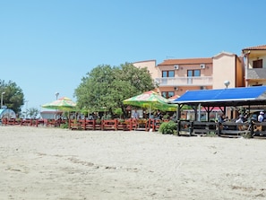 Un restaurant situé au bord de la plage, avec une terrasse et un bâtiment en arrière-plan.