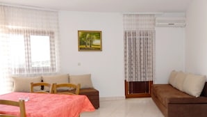 A living room with a dining table, two sofas, and a painting on the wall. - Apartments Idila (Medulin)
