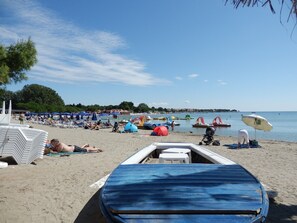 Une plage avec des transats, des parasols et un bateau.